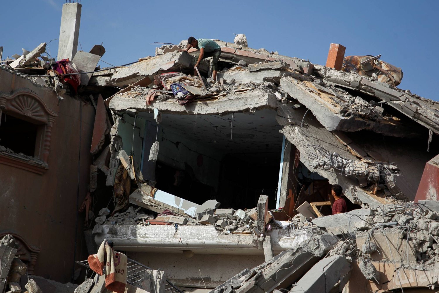 فلسطينيون يتفقدون موقع غارة إسرائيلية على منزل في رفح جنوب قطاع غزة الأحد (رويترز)